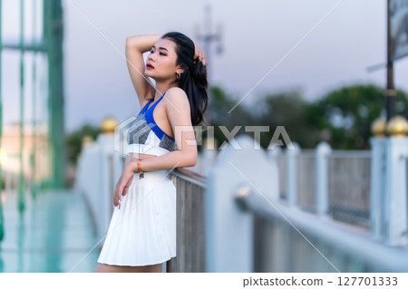 Portrait of beautiful athletic young asian woman in fashionable sportswear standing and having rest after exercise training on Route walking jogging or ride bicycle and exercise on the bridge. 127701333
