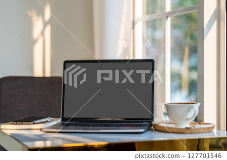 Mockup of laptop computer with empty screen with coffee cup and smartphone on table beside the window of the coffee shop background,Black gray screen Mockup of laptop computer with empty screen with coffee cup and smartphone on table beside the window of the coffee shop background,Black gray screen 127701546