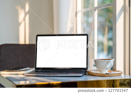 Mockup of laptop computer with empty screen with coffee cup and smartphone on table beside the window of the coffee shop background,White screen 127701547