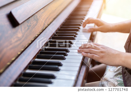 Close-up of hands woman wearing brownish green dress stylish hipster with playing old wooden piano Vintage classic style. Close-up of hands woman wearing brownish green dress stylish hipster with playing old wooden piano Vintage classic style. 127701748