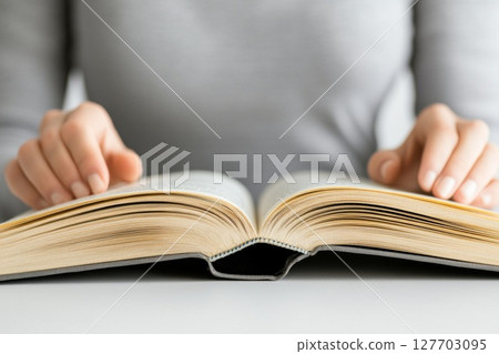 Open book held by hands with soft focus background showcasing reading and knowledge exploration 127703095
