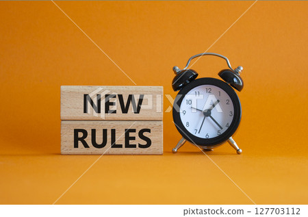 New rules symbol. Concept word New rules on wooden blocks. Beautiful orange background with alarm clock. Business and New rules concept. Copy space 127703112
