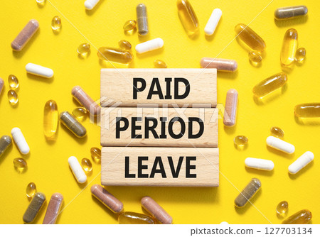 Paid Period Leave symbol. Concept words Paid Period Leave on wooden blocks. Beautiful yellow background with pills. Healthcare and Paid Period Leave concept. Copy space. 127703134