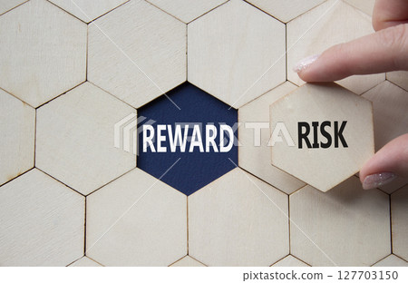 Risk or Reward symbol. Concept word Risk or Reward on wooden comb puzzle. Businessman hand. Beautiful deep blue background. Business and Risk or Reward concept. Copy space 127703150