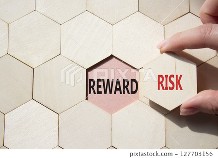 Risk or Reward symbol. Concept word Risk or Reward on wooden comb puzzle. Businessman hand. Beautiful pink background. Business and Risk or Reward concept. Copy space 127703156