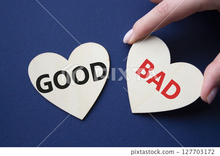 Good or Bad symbol. Concept word Good or Bad on wooden hearts. Businessman hand. Beautiful deep blue background. Business and Good or Bad concept. Copy space 127703172