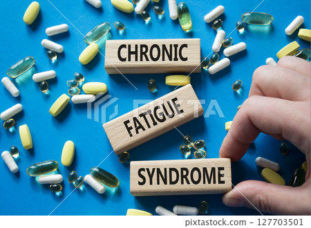 Chronic Fatigue Syndrome symbol. Concept word Chronic Fatigue Syndrome on wooden blocks. Doctor Hand. Beautiful blue background with pills. Medicine and Chronic Fatigue Syndrome concept. Copy space 127703501