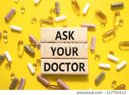 Ask Your Doctor symbol. Concept word Ask Your Doctor on wooden blocks. Beautiful yellow background with pills. Medicine and Ask Your Doctor concept. Copy space 127703512