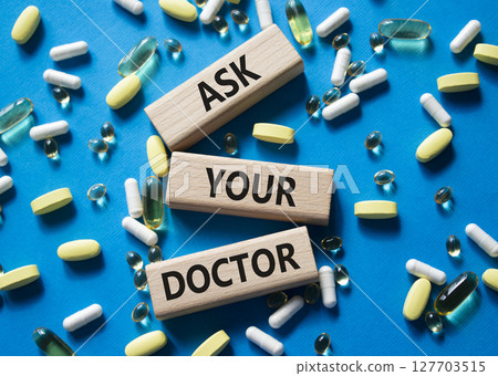 Ask Your Doctor symbol. Concept word Ask Your Doctor on wooden blocks. Beautiful blue background with pills. Medicine and Ask Your Doctor concept. Copy space 127703515