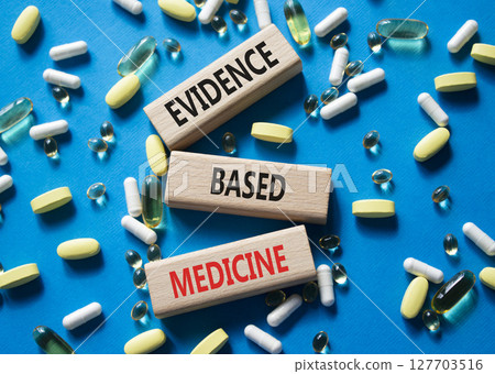 Evidence Based Medicine symbol. Concept word Evidence Based Medicine on wooden blocks. Beautiful blue background with pills. Medicine and Evidence Based Medicine concept. Copy space 127703516