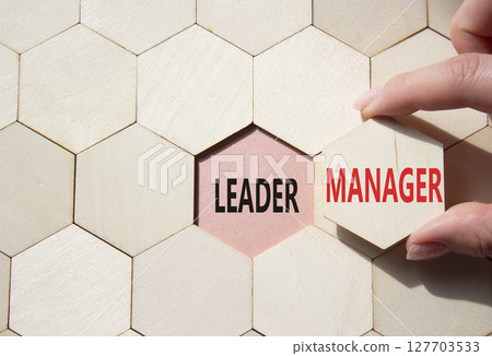 Leader or Manager symbol. Concept word Leader or Manager on wooden comb puzzle. Businessman hand. Beautiful pink background. Business and Leader or Manager concept. Copy space 127703533