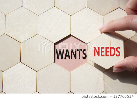 Wants and Needs symbol. Concept word Wants and Needs on wooden comb puzzle. Businessman hand. Beautiful pink background. Business and Wants and Needs concept. Copy space 127703534