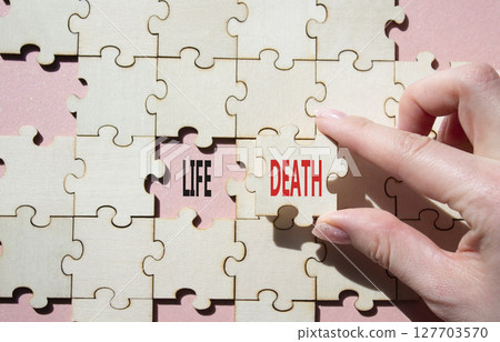 Life or Death symbol. Concept word Life or Death on wooden puzzle. Businessman hand. Beautiful pink background. Business and Life or Death concept. Copy space Life or Death symbol. Concept word Life or Death on wooden puzzle. Businessman hand. Beautiful pink background. Business and Life or Death concept. Copy space 127703570
