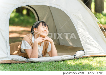 A girl lying down and relaxing in a tent at a campsite 127703705