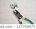 Pliers and screws on a wooden board 127704075