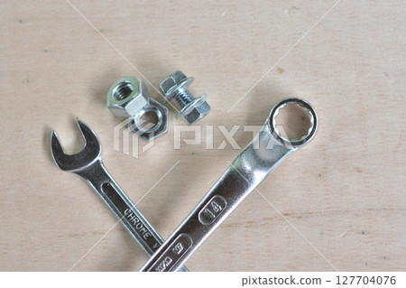 Wrench and screws on a wooden board 127704076