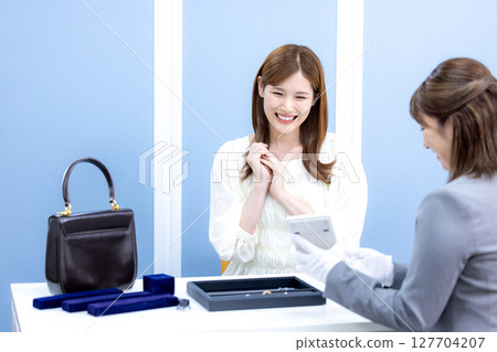 一位女士正在接受買家的包包和貴金屬估價 127704207