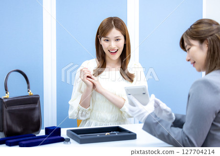 一位女士正在接受買家的包包和貴金屬估價 一位女士正在接受買家的包包和貴金屬估價 127704214