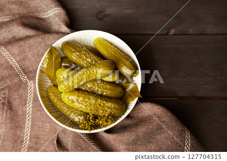 Marinated cucumbers in a bowl on a dark wooden background. Homemade pickles. 127704315