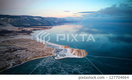 Frozen Lake Baikal from the air. Transparent ice, in which clouds are reflected. Winter trip. 127704664