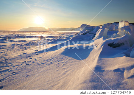 Winter landscape. Frozen Lake Baikal covered with snow at sunset. 127704749