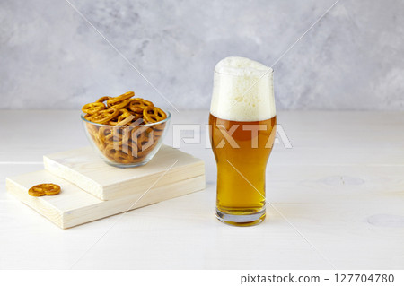 A glass of light beer with pretzels on a white wooden background A glass of light beer with pretzels on a white wooden background 127704780