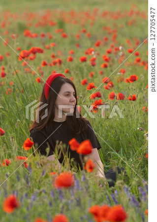 Young Woman in Poppy Field with Red Hat 127705477