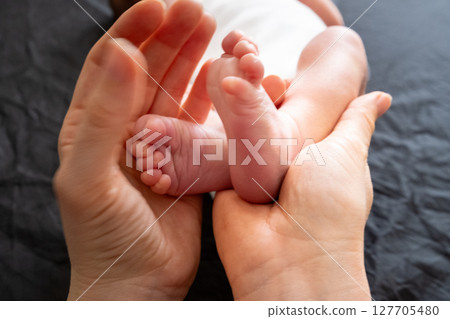 Tender Moment: Adult Hands Holding Newborn Baby Feet 127705480