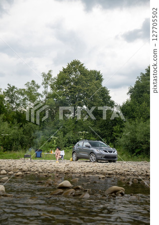 Camping by the River with SUV and Campfire 127705502