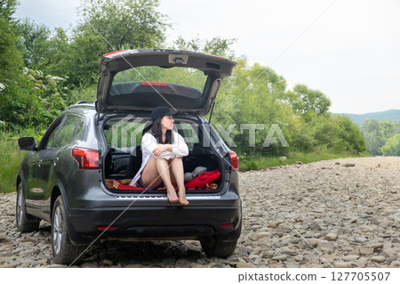 Woman Relaxing in SUV Trunk on Rocky Path 127705507