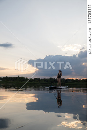 Paddleboarding at Sunset on a Tranquil Lake 127705525