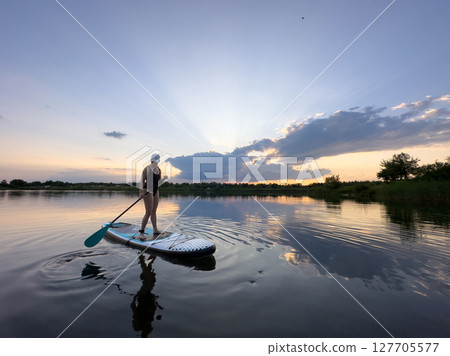 Paddleboarding at Sunset on a Tranquil Lake 127705577
