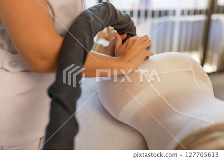 Woman in special white suit getting anti cellulite massage in a spa salon. LPG, and body contouring treatment in clinic.Reset body weight with LPG massage.  127705613