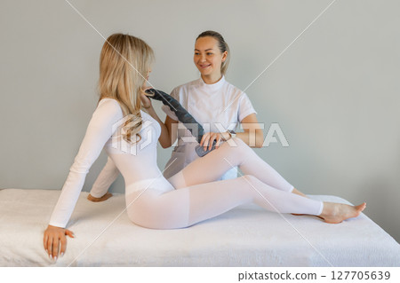 Woman in special white suit getting anti cellulite massage in a spa salon. LPG, and body contouring treatment in clinic.Reset body weight with LPG massage.  127705639