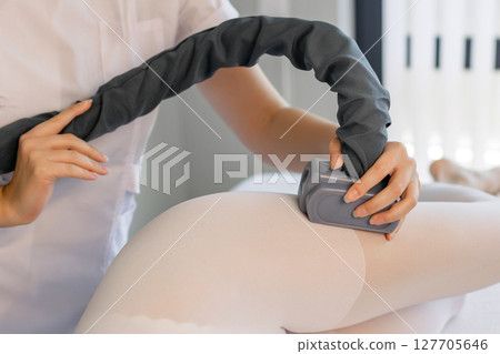 Woman in special white suit getting anti cellulite massage in a spa salon. LPG, and body contouring treatment in clinic.Reset body weight with LPG massage.  127705646