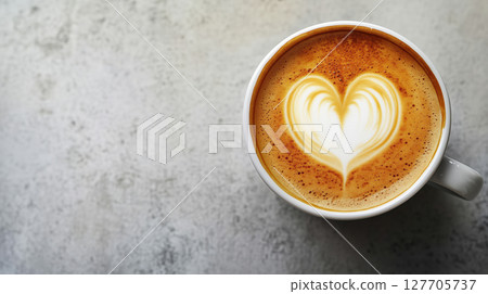 Cup of cappuccino or latte with heart-shaped milk foam art on textured gray surface. Cozy morning drink with elegant coffee presentation. Love and warmth. Cup of cappuccino or latte with heart-shaped milk foam art on textured gray surface. Cozy morning drink with elegant coffee presentation. Love and warmth. 127705737