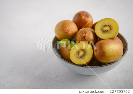 Fresh golden kiwifruit arranged in a rustic bowl, showcasing vibrant colors and textures, perfect for healthy eating and culinary inspiration Fresh golden kiwifruit arranged in a rustic bowl, showcasing vibrant colors and textures, perfect for healthy eating and culinary inspiration 127705762