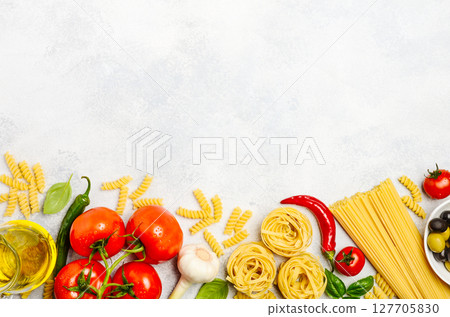 Fresh ingredients for Italian cuisine arranged on a light background, featuring pasta, tomatoes, garlic, and herbs for culinary inspiration 127705830