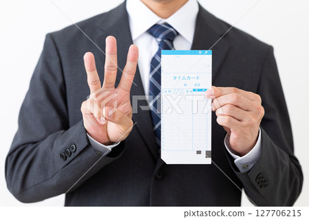 A middle-aged male businessman in a suit holding a time card and showing three fingers A middle-aged male businessman in a suit holding a time card and showing three fingers 127706215