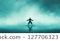 Martial artist performs in silhouette on calm water at dawn surrounded by misty fog creating a serene atmosphere with reflection 127706323
