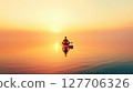 Serene meditation at sunset on tranquil water with warm hues illuminating the horizon and creating a peaceful atmosphere 127706326