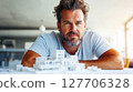 Architect focuses on building model while working in modern office, showcasing creativity and design skills during a bright morning in an urban setting 127706328