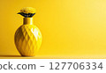 Bright yellow vase with a daisy flower against a vibrant yellow backdrop creating a cheerful and inviting atmosphere 127706334