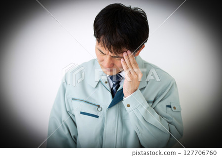 一位身穿綠色工作服的憂心忡忡的中年男性商人 一位身穿綠色工作服的憂心忡忡的中年男性商人 127706760