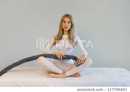 Woman in white suit for LPG massage. Anti-cellulite body care concept. Gray background 127706883
