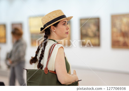 Portrait of a young Caucasian surprised woman in a straw hat and elegant clothes in the gallery of modern art. The concept of the Museum Day Portrait of a young Caucasian surprised woman in a straw hat and elegant clothes in the gallery of modern art. The concept of the Museum Day 127706936