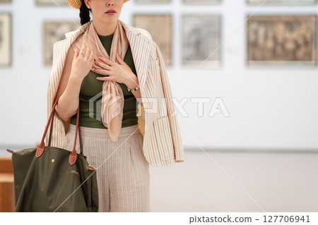 Close up of young Caucasian woman looks at an exhibition of paintings in a modern gallery in bewilderment and embarrassment. Concept of museum day Close up of young Caucasian woman looks at an exhibition of paintings in a modern gallery in bewilderment and embarrassment. Concept of museum day 127706941