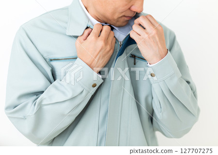 A middle-aged male businessman wearing green work clothes and concerned about body odor 127707275