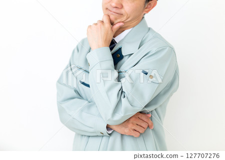 A worried middle-aged male businessman wearing green work clothes 127707276
