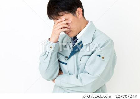 A worried middle-aged male businessman wearing green work clothes A worried middle-aged male businessman wearing green work clothes 127707277